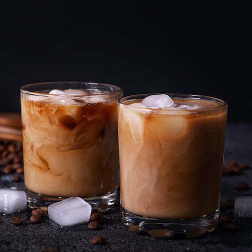 Iced coffee in a tall glass with cream poured over