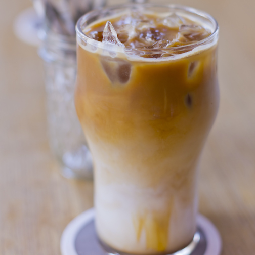 A delicious cafe latte with out of focus traditional paper straws in the background.